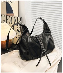 Detail of minimalist black soft leather hobo bag with sleek metal zipper and adjustable strap