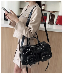 Detail of black patent leather tote bag featuring silver rivets and punk style multi-zippers