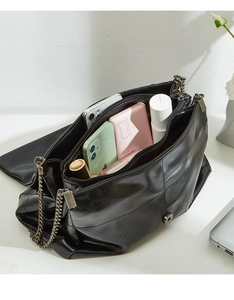 Interior detail of large capacity black leather bag with metal chain and compartments