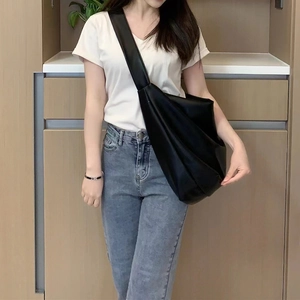 Modern black oversized hobo bag in soft leather with wide shoulder strap on model