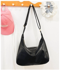 Détail du sac hobo noir avec bandoulière réglable suspendu à un crochet en bois