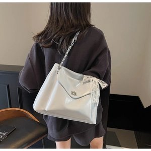 Detail of large white bow tote bag with metallic chain strap and lace accents