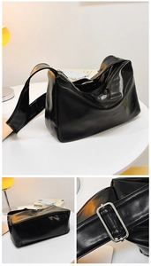 Detail view of glossy black tote bag featuring wide adjustable strap and silver hardware