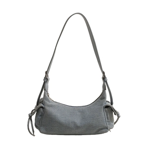 Detail of grey denim crescent shoulder bag with adjustable strap and side drawstring pocket