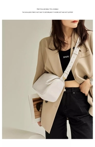 Detail of white leather crossbody bag with wide shoulder strap on beige blazer