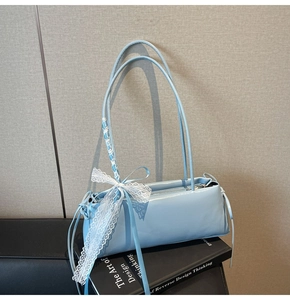 Detail of light blue glossy baguette bag with white lace bow and silk ribbon straps