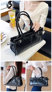 Detailansicht der glänzenden schwarzen Ledertasche mit Metallschnalle und feinen Nähten