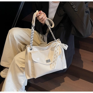 Detail of off-white tote bag featuring lace bow decoration and metal twist lock