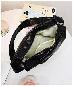 Interior view of black tote bag showing green lining, zipper pocket, and spacious storage