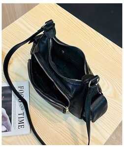 Macro detail of black vintage leather bag showing multiple zip compartments and gold hardware