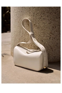Detailed view of cream leather shoulder bag featuring golden heart metal hardware