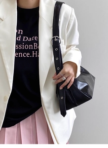 Detail of black glossy leather bag with wide strap and silver metal eyelets