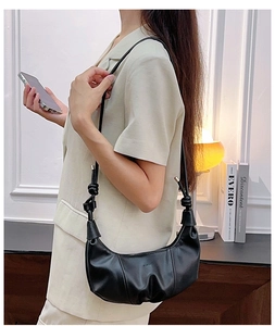 Detail of black croissant hobo bag featuring elegant ruched texture and knotted strap