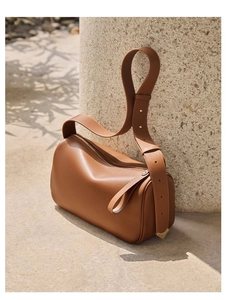 Detail of caramel brown leather handbag with adjustable wide strap and gold hardware