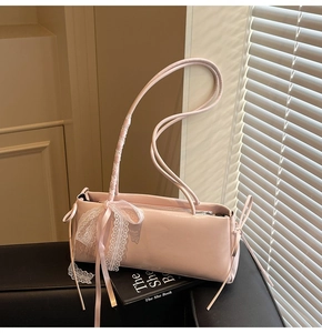 Detailed view of pink patent leather bag featuring delicate white lace and ribbon accents