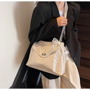 Detail view of cream white tote bag with silver twist lock and lace bow decoration
