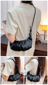 Detailed close-up of the pleated texture and knot detail on a black crescent shoulder bag