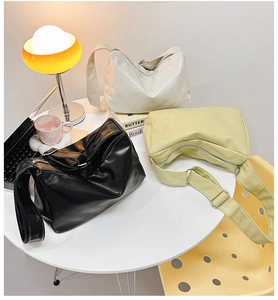 Detailed shot of three minimalist soft leather tote bags in black, white, and cream yellow