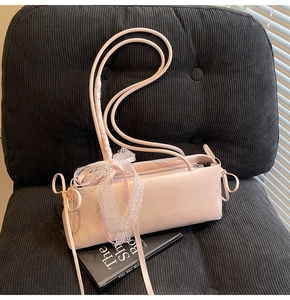 Detail view of pink baguette shoulder bag with white lace bow on black background