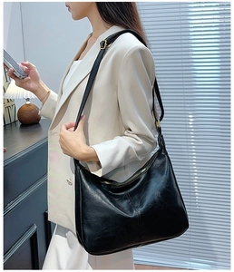 Détail d'un sac hobo noir minimaliste avec fermeture éclair dorée porté à l'épaule