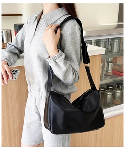 Detail of a chic black faux leather tote with adjustable strap worn by a model