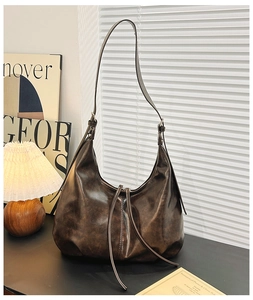 Detail of dark brown vintage hobo bag with long zipper tassels on a minimalist desk