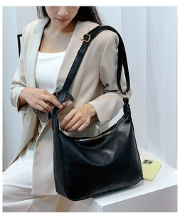 Détail du sac cabas noir avec bandoulière réglable et boucle en métal doré sur le mannequin