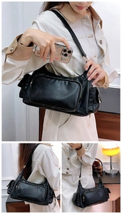 Detail of black vintage shoulder bag featuring a large zipper pocket and golden hardware