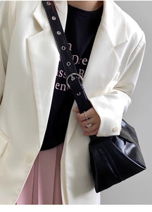Detail of black underarm bag featuring wide shoulder strap with metal eyelets and buckle