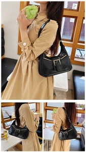 Détail du sac croissant noir en cuir froissé brillant avec boucles métalliques décoratives