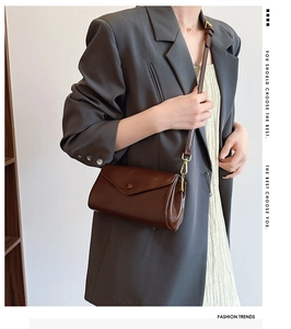Close-up of brown leather crossbody bag with golden hardware on a stylish model