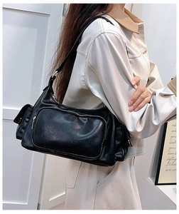 Detail of a black multi-pocket shoulder bag in soft PU leather with metal zippers