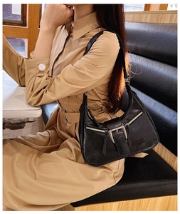 Détail d'un sac bandoulière en cuir PU noir avec boucle métallique et fermetures éclair