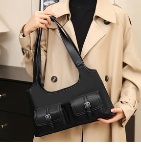Close-up of vintage black leather shoulder bag with double buckle pockets on a model
