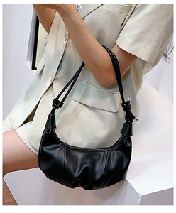 Detail of black crescent croissant bag with knot design on shoulder strap shown on model