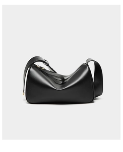 Close-up of black matte leather bag showing soft folded structure and gold zipper hardware