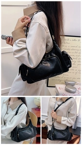 Detail of black multi-pocket shoulder bag with glossy finish and functional zippers
