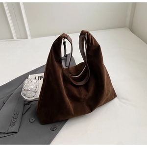 Détail d'un sac cabas en daim marron foncé avec sangle en cuir et fermeture éclair