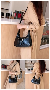 Détail du sac croissant en PU noir avec boucles argentées et finitions zippées au café