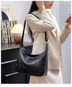 Détail du sac hobo en cuir ciré noir porté par un mannequin dans un cadre élégant
