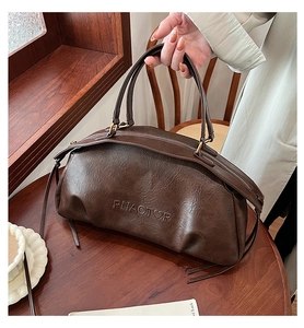 Gros plan sur la texture cuir vintage marron foncé et le logo embossé sur le sac