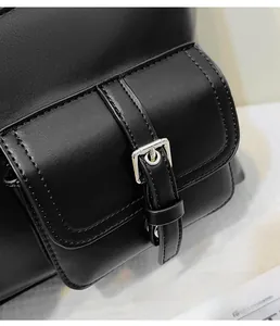 Close-up of black leather texture with silver metal buckles and stitching on a tote bag