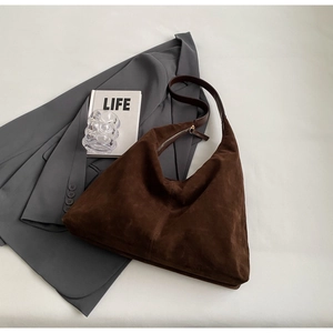 Détail d'un sac hobo en daim marron foncé avec bandoulière en cuir et mise en scène urbaine