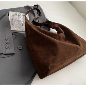 Détail du grand sac cabas en daim marron foncé avec texture mate sur blazer gris