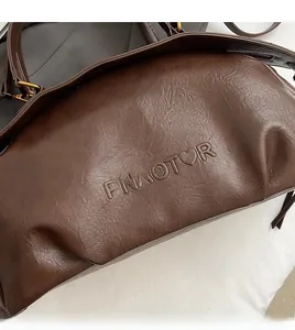 Gros plan du logo PNAOTOR sur un sac en cuir marron foncé avec une texture froissée