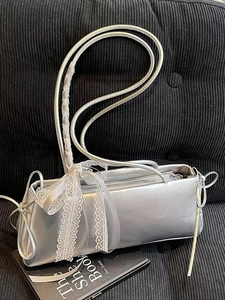 Silver rectangular baguette bag with white lace bow detail on black velvet background