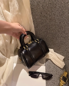 Close-up of a glossy black Boston bag with gold zippers and premium leather texture