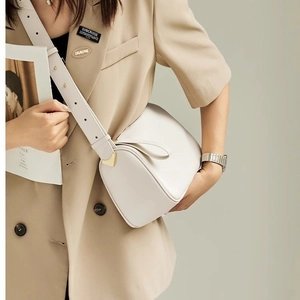 Chic beige cylinder crossbody bag with gold hardware worn with a khaki blazer