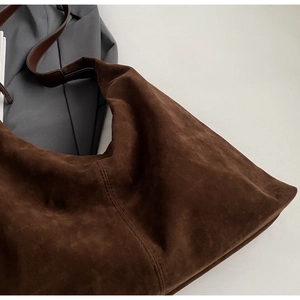Détail du cabas en daim marron foncé montrant les doubles coutures du bracelet en cuir