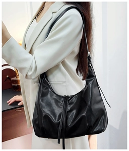 Detail of soft black leather hobo bag featuring vertical lines and adjustable shoulder strap